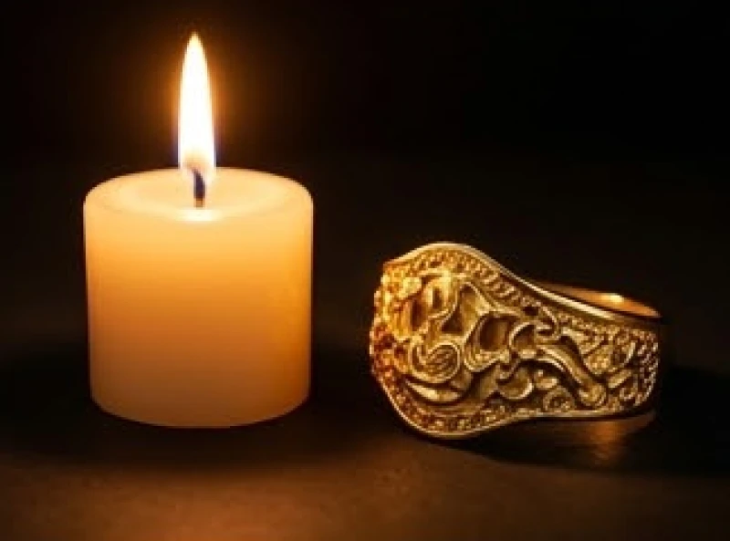 Hình ảnh ngọn nến đang cháy sáng rực bên cạnh một món đồ trang sức bằng vàng đúc tinh xảo