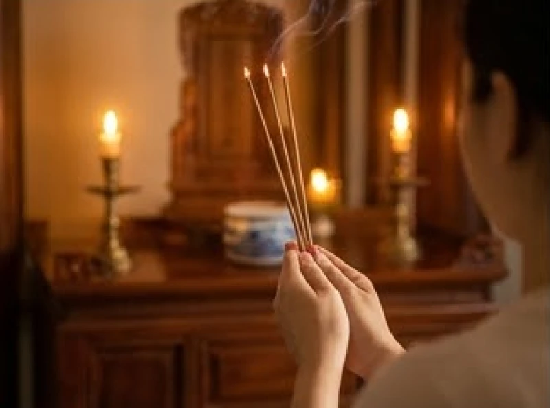Người đàn ông mặc trang phục lịch sự đang chắp tay vái lạy trước bàn thờ gia tiên
