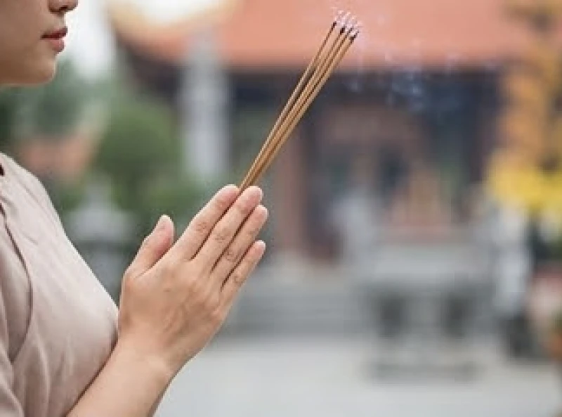 Người phụ nữ chắp tay thành kính khấn nguyện cầu bình an và tài lộc tại không gian tâm linh linh thiêng.