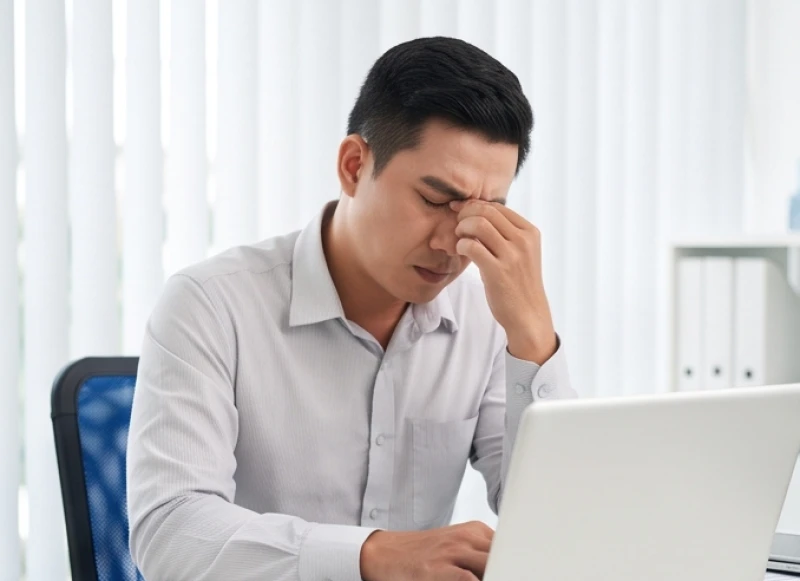 Nam nhân viên văn phòng lộ rõ vẻ mệt mỏi khi các vùng cơ quanh mí mắt và gò má bị căng cứng liên tục