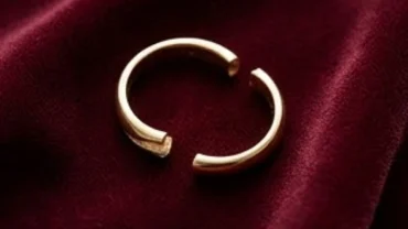 Chiếc nhẫn vàng 18k bị gãy làm đôi trên nền vải nhung phản ánh thắc mắc nhẫn bị gãy là điềm gì
