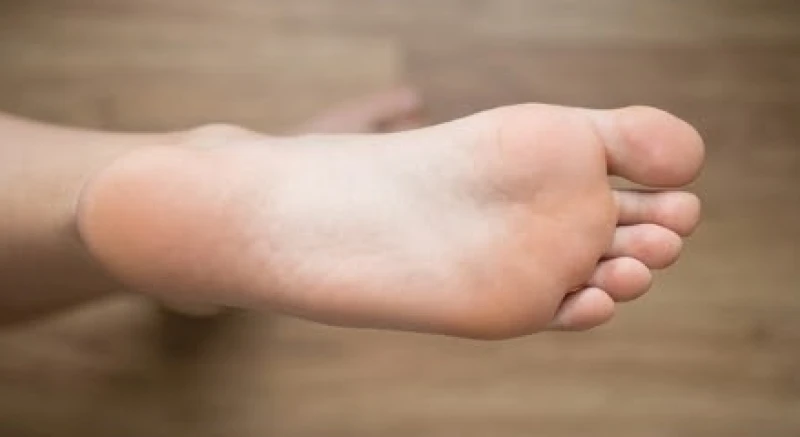 Lòng bàn chân khỏe mạnh tiếp xúc với mặt sàn gỗ phẳng đại diện cho sự vững chãi