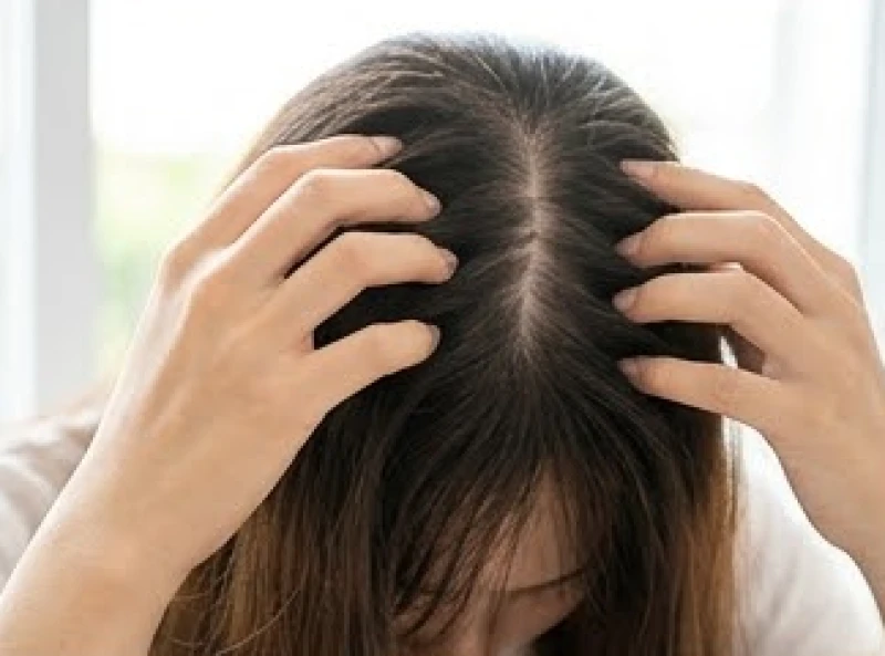 Bệnh nhân dùng tay gãi nhẹ lên vùng da đầu đang bị ngứa rát xung quanh nốt ruồi