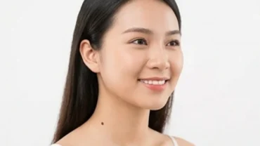 Phụ nữ có nốt ruồi ở cổ bên trái đang mỉm cười nhẹ nhàng trong không gian ngập tràn ánh sáng tự nhiên