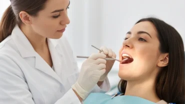 Bác sĩ nha khoa dùng gương nha khoa kiểm tra nốt ruồi ở lưỡi cho bệnh nhân