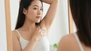 Nữ giới kiểm tra nốt ruồi ở nách trước gương để theo dõi tình trạng sức khỏe và yếu tố phong thủy