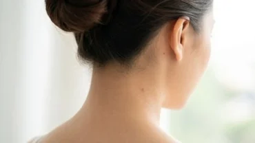 Góc chụp từ phía sau lưng một người phụ nữ lộ rõ nốt ruồi sau gáy bên phải thanh tú