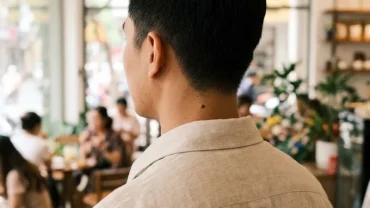 Cận cảnh nốt ruồi sau gáy nam trên nền không gian quán cà phê hiện đại tại Việt Nam