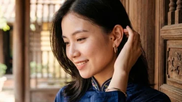 Người phụ nữ có nốt ruồi sau tai mỉm cười nhẹ nhàng thể hiện tướng mạo tài lộc và phú quý trong nhân tướng học