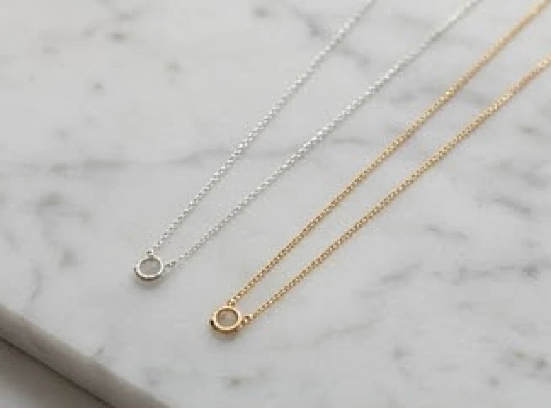 Sợi dây chuyền vàng và dây chuyền bạc đặt cạnh nhau để so sánh về độ bền và ý nghĩa phong thủy