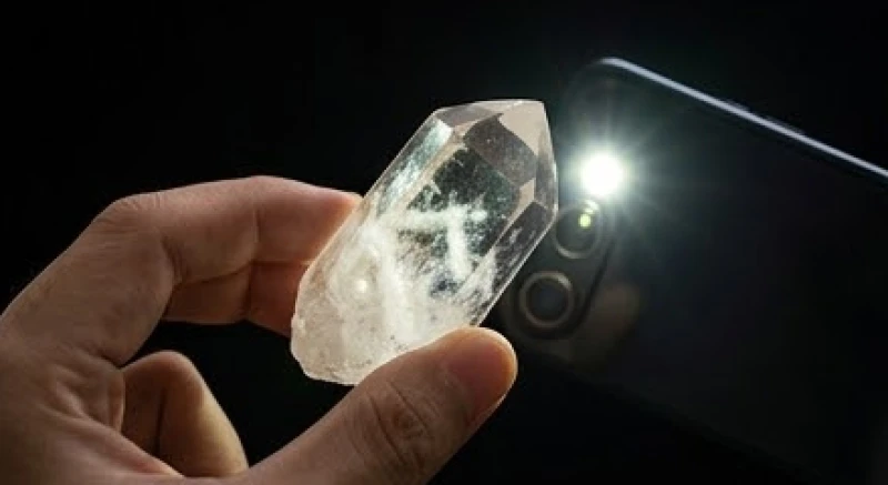 Dùng đèn flash điện thoại soi xuyên qua viên đá thạch anh tự nhiên để quan sát vân mây bên trong