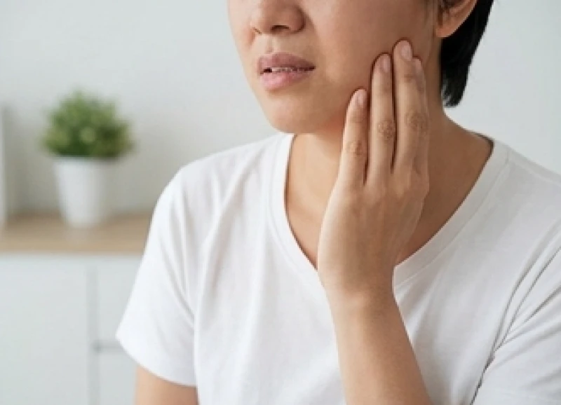 Bệnh nhân bị răng quặp đưa tay ôm má thể hiện sự khó chịu do mỏi cơ hàm khi nhai thức ăn