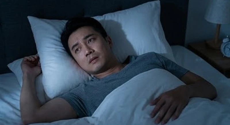 Người đàn ông trằn trọc khó ngủ trên giường khi trăn trở về những áp lực gia đình và mối quan hệ người thân