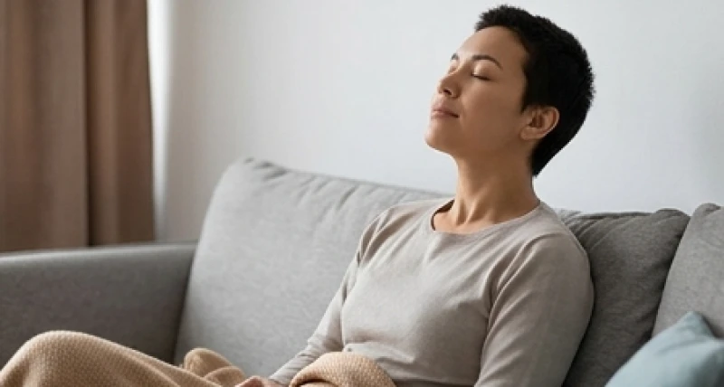 Mơ thấy mình tự sát: Giải mã chi tiết tâm lý, sổ mơ và hotline 1 Một người đang thư giãn hít thở sâu trên ghế sofa, đại diện cho việc vượt qua cảm giác hoang mang tột độ sau giấc mộng.