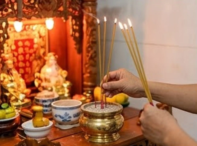 Văn khấn tất niên tại cửa hàng: Bài cúng chuẩn chiêu tài lộc 7 Chủ cửa hàng cầm ba nén hương trang nghiêm cắm vào bát nhang tại ban Thần Tài bên trong khu vực buôn bán