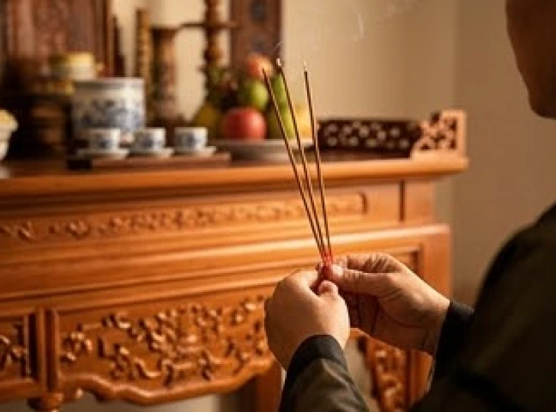 Văn khấn mời gia tiên về thụ hưởng lễ vật: Trình tự cúng trọn vẹn 1 Gia chủ thành kính chắp tay thắp hương trước bàn thờ gia tiên với khói nhang bay nhẹ