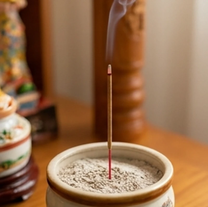 Một nén hương đang cháy sáng rực được cắm ngay ngắn vào giữa bát hương trên ban thờ Thần Tài