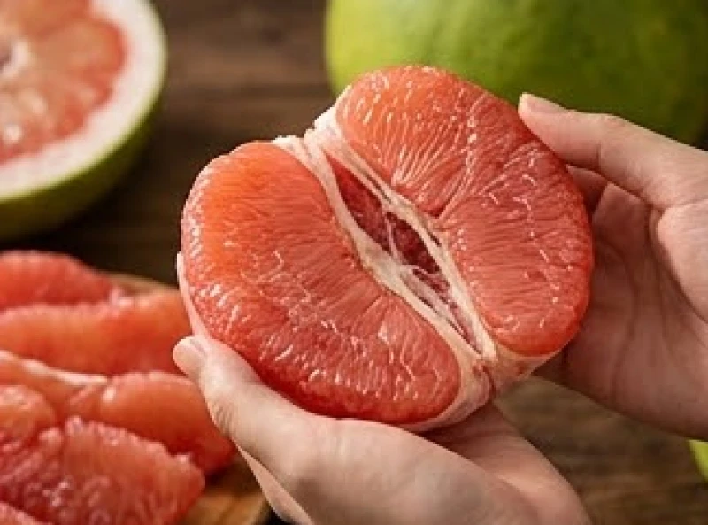 Bàn tay đang nhẹ nhàng tách rời từng tép bưởi căng mọng nước màu hồng ngọc vô cùng bắt mắt