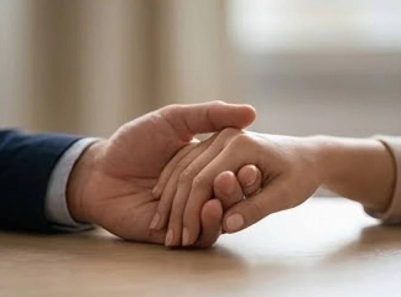 Hai bàn tay nam và nữ đan vào nhau trên bàn phản ánh sự căng thẳng và thiếu đồng điệu