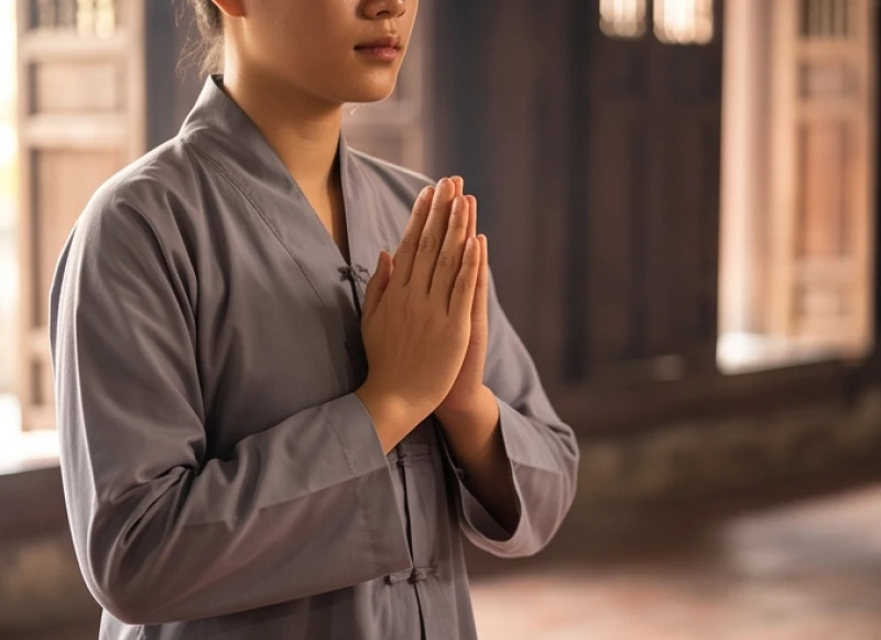 Phụ nữ mặc bộ đồ lam đi chùa màu xám nhã nhặn chắp tay cầu nguyện thành tâm tại đền phủ