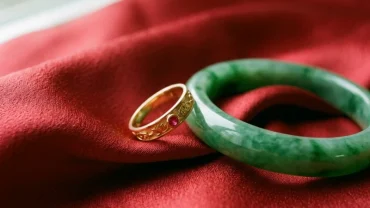 Các mẫu trang sức phong thủy cho tuổi tỵ như vòng đá thạch anh nhẫn vàng tinh xảo xếp trên nền lụa đỏ