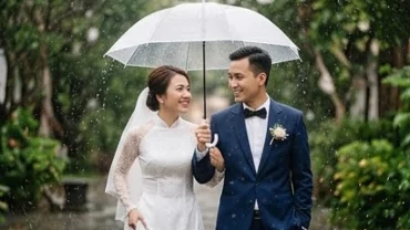 Cô dâu và chú rể che ô mỉm cười hạnh phúc, giải đáp thắc mắc trời mưa trong ngày cưới là điềm gì