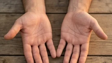 Hai bàn tay vuông vức khỏe khoắn đặt trên mặt bàn gỗ với nếp chỉ tay rõ nét
