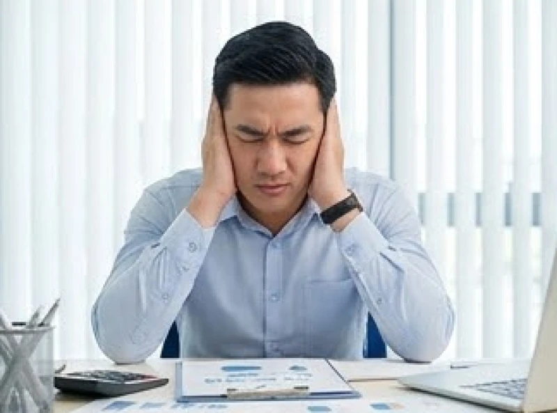 Ù tai là điềm gì: Tra cứu theo giờ và góc nhìn y khoa 5 Người đàn ông căng thẳng ôm chặt cả hai tai do áp lực công việc và tiếng ồn ảo dội vang