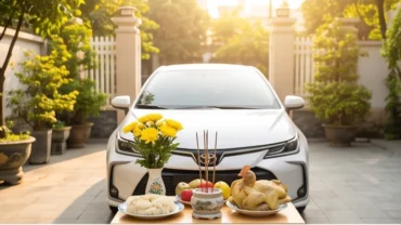 Lễ cúng xe ô tô mới mua với mâm đồ cúng tươm tất gồm xôi chè, gà luộc, trái cây và hoa tươi đặt trước mũi xe