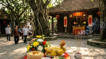 Mâm cúng mặn truyền thống và người dân đang dâng hương chuẩn bị đọc văn khấn đình làng tại không gian linh thiêng