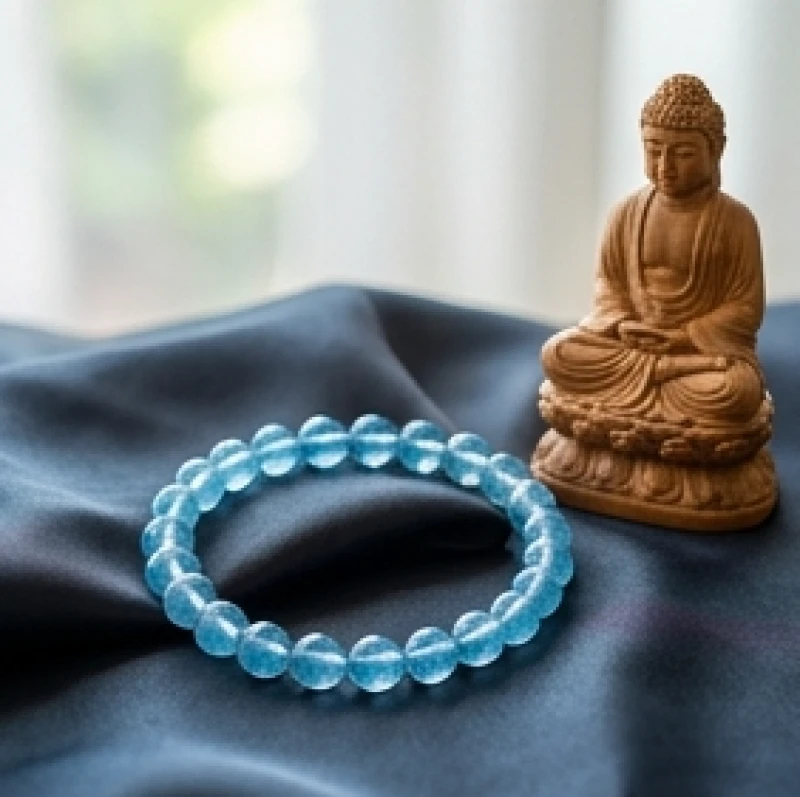 Vòng tay đá Aquamarine xanh biếc thanh tao đặt cạnh một bức tượng Phật Phổ Hiền Bồ Tát nhỏ