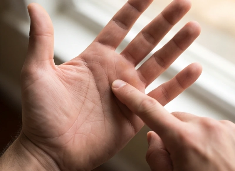 Ngón tay trỏ đang chỉ vào gốc ngón giữa trên lòng bàn tay nơi đường vận mệnh hướng tới