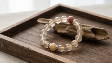 Vòng tay đá phong thủy tuổi hợi chế tác từ đá thạch anh tự nhiên đặt trên khay gỗ trầm hương