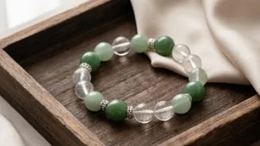 Vòng tay đá phong thủy tuổi Mùi chế tác từ ngọc bích và thạch anh tự nhiên đặt trên khay gỗ mộc