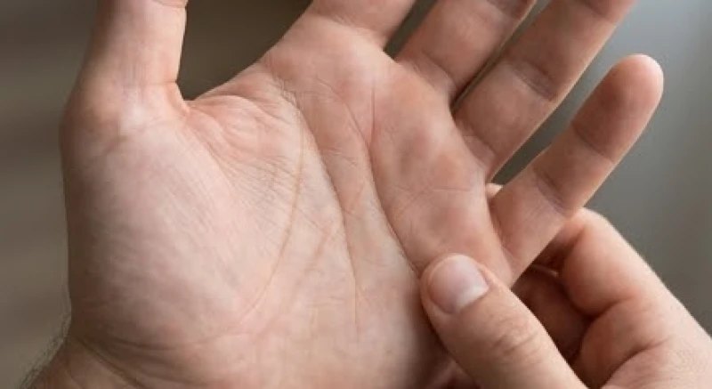 Người xem chỉ tay đang quan sát kỹ đường công danh chạy dọc giữa lòng bàn tay để phân tích vận mệnh