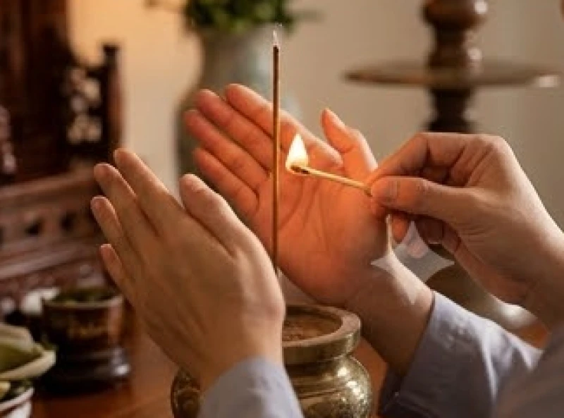 Gia chủ nhẹ nhàng dùng hai tay che gió và châm lại lửa cho nén nhang bị tắt giữa chừng